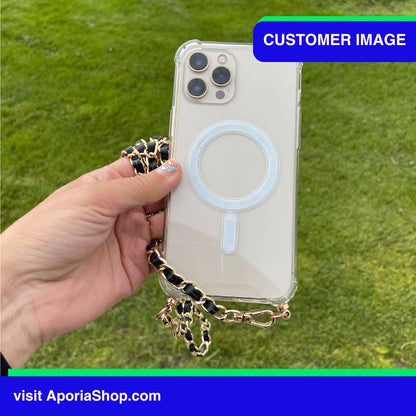 Image of customer holding the Aporia MagSafe Clear Case - Luxury Crossbody Strap for iPhone 15/14/13/12 outside in a greenery park