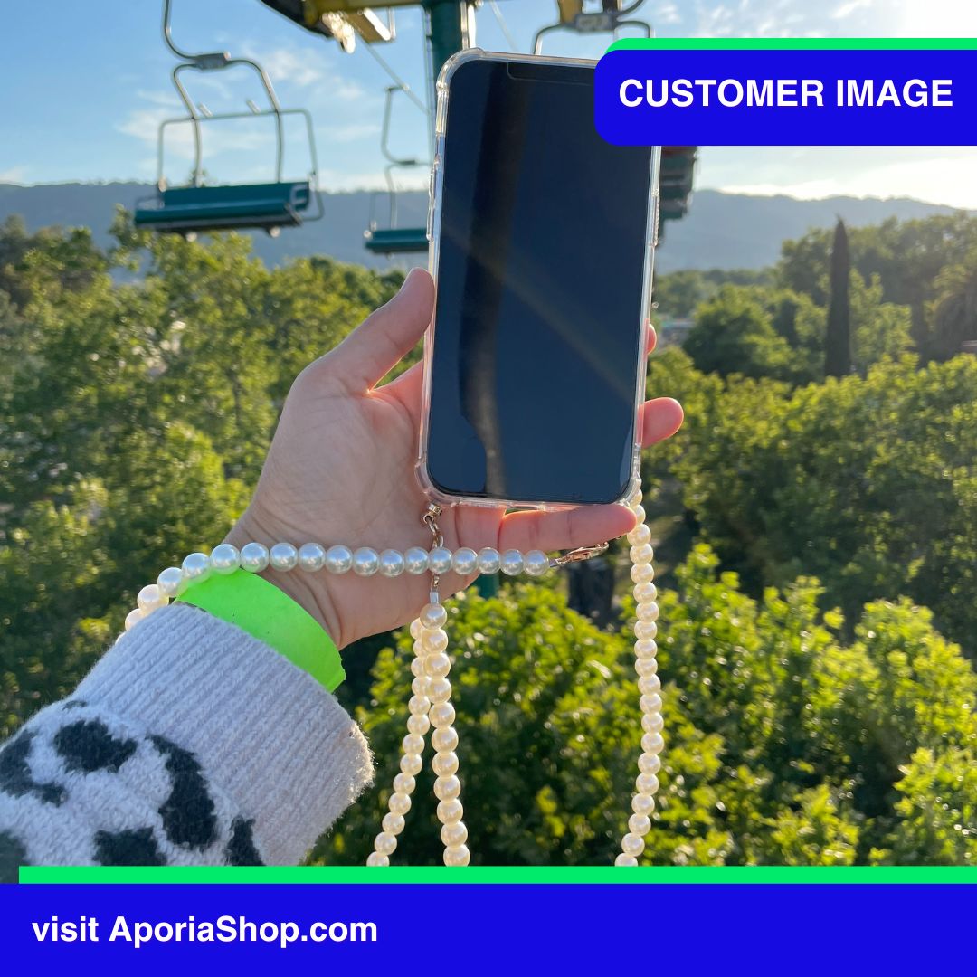 Image of customer holding Aporia Magsafe Clear Case - Pearl Crossbody Strap for iPhone 15/14/13/12 while riding chairlift zipline