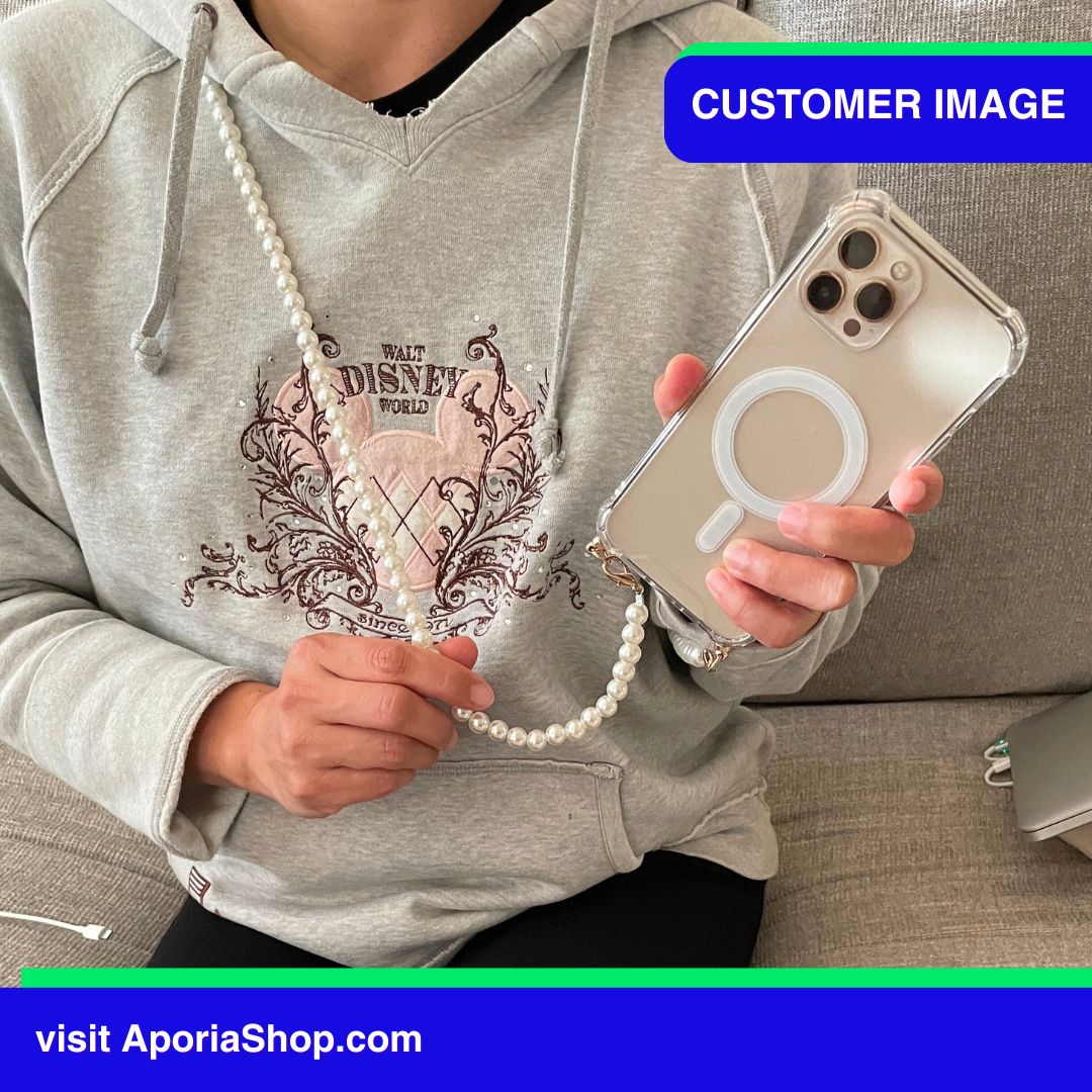 Image of customer holding the Aporia Magsafe Clear Case - Pearl Crossbody Strap for iPhone 15/14/13/12 while on a lobby